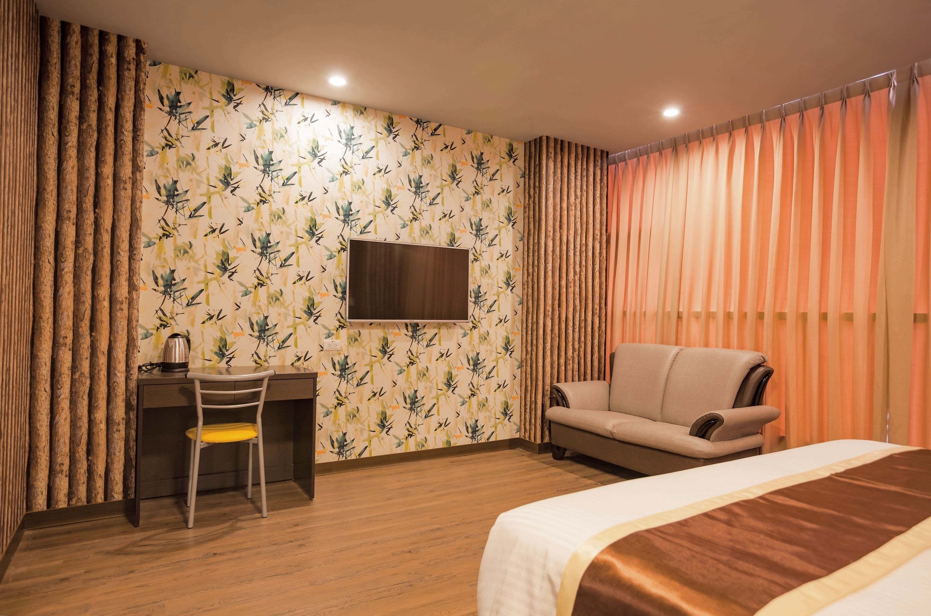 Hotellihuone, jossa on sänky, työpöytä, tuoli, televisio ja verhot.