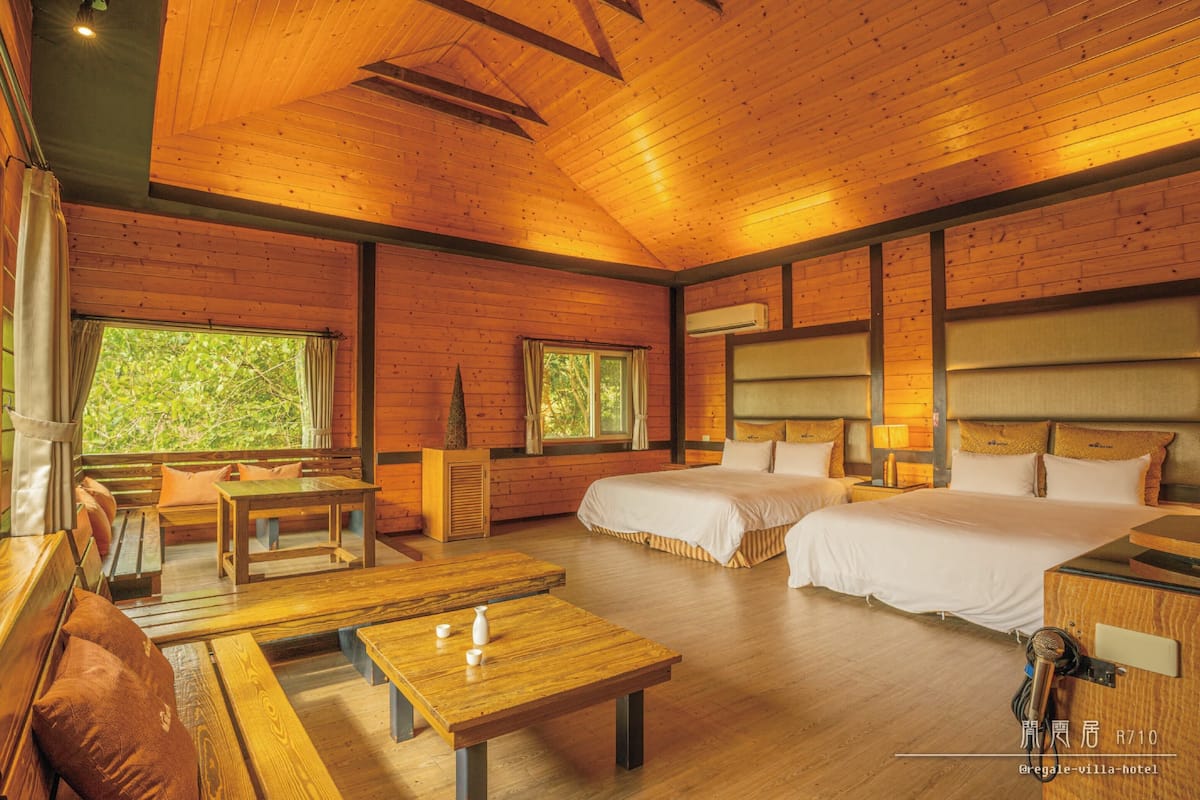 Een houten kamer in chaletstijl met twee bedden, een eettafel en een bank.
