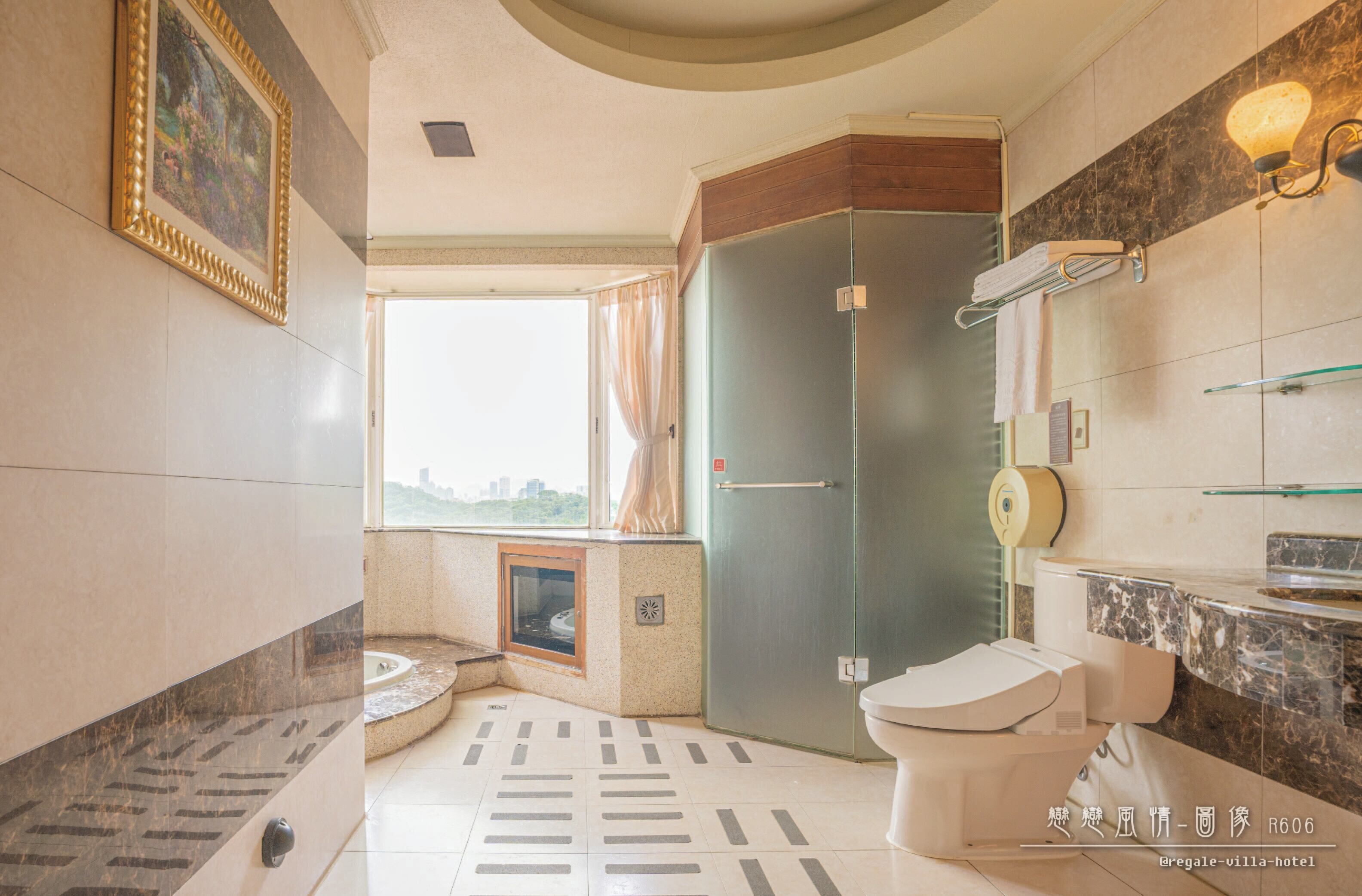 A modern bathroom with a toilet, sink, and shower area. There is a window with curtains, a painting on the wall, and a marble floor.