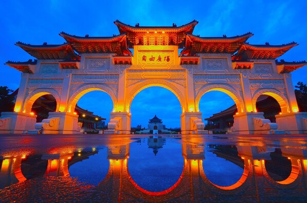 Een traditionele Chinese poort met ingewikkelde versieringen en een spiegelbeeld in het water.