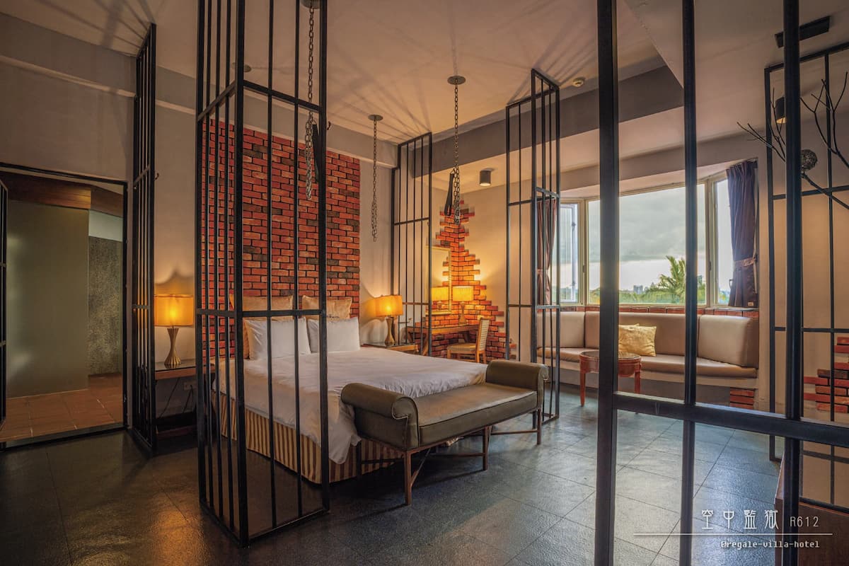 Een hotelkamer met een bed, een bank, een bureau en uitzicht op het omliggende landschap.