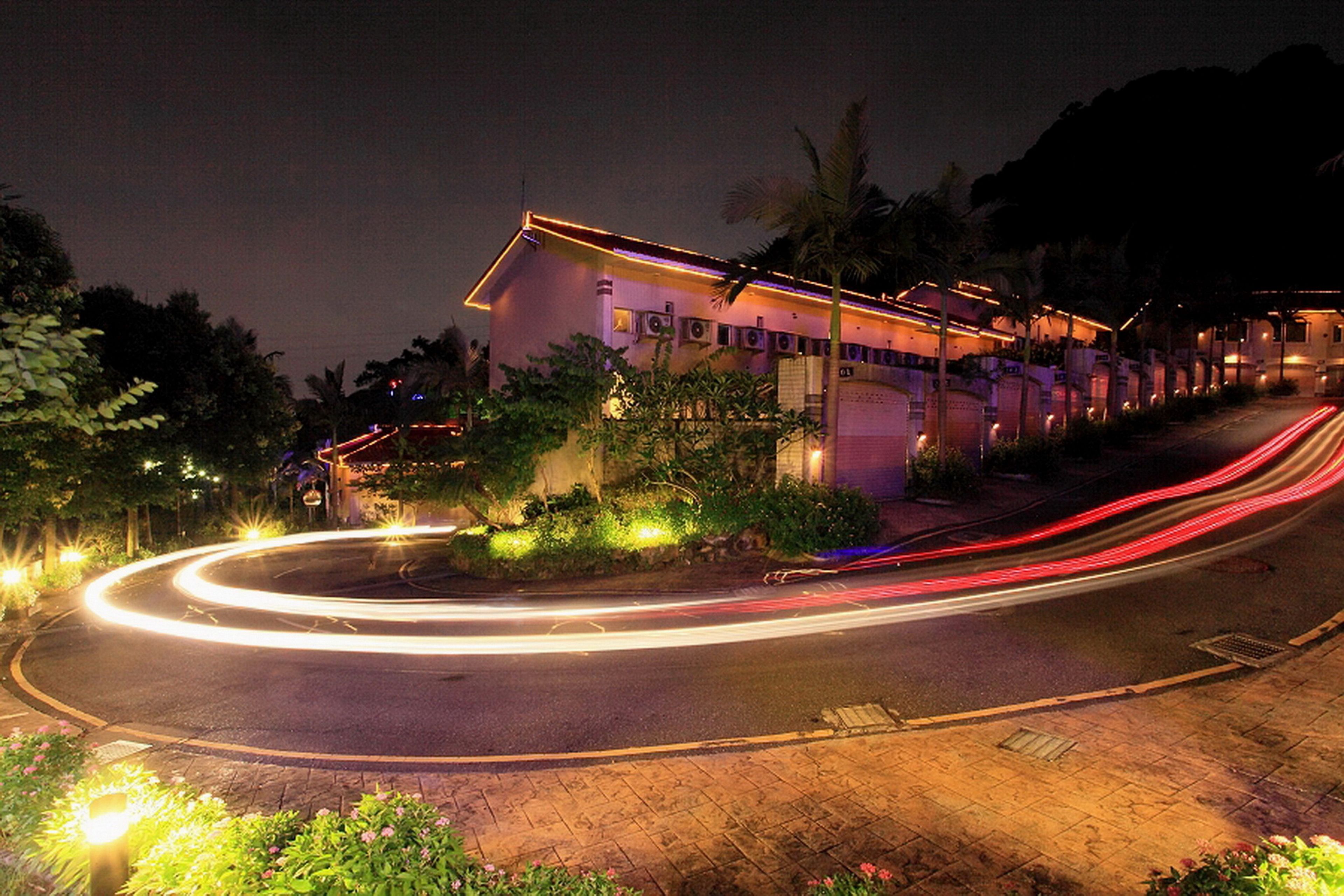 A building with a curved roof and a lighted pathway leading to it.