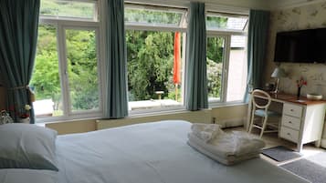 Een hotelkamer met een groot bed, een bureau met stoel, een televisie en een raam met gordijnen.