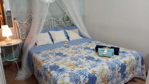 A bedroom with a bed, a bedside table, a lamp, and a canopy.