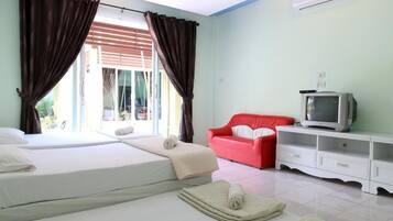 A hotel room with two beds, a red sofa, a TV, and a balcony with curtains.