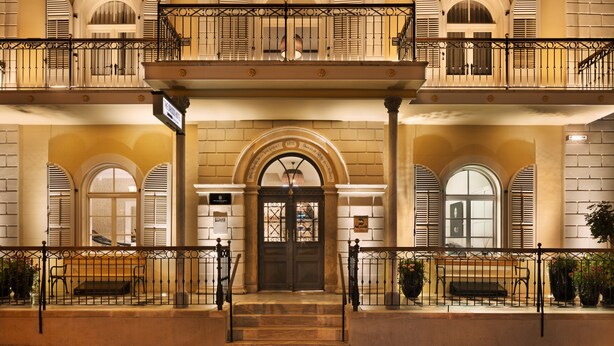A grand entrance with a double staircase leading to a balcony, flanked by arched windows and a central door with a decorative iron grille. - The Drisco Hotel Tel Aviv - Relais & Châteaux (Tel Aviv)