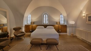 A spacious bedroom with a large bed, two bedside tables, a chair, and a floor lamp. - The Drisco Hotel Tel Aviv - Relais & Châteaux (Tel Aviv)