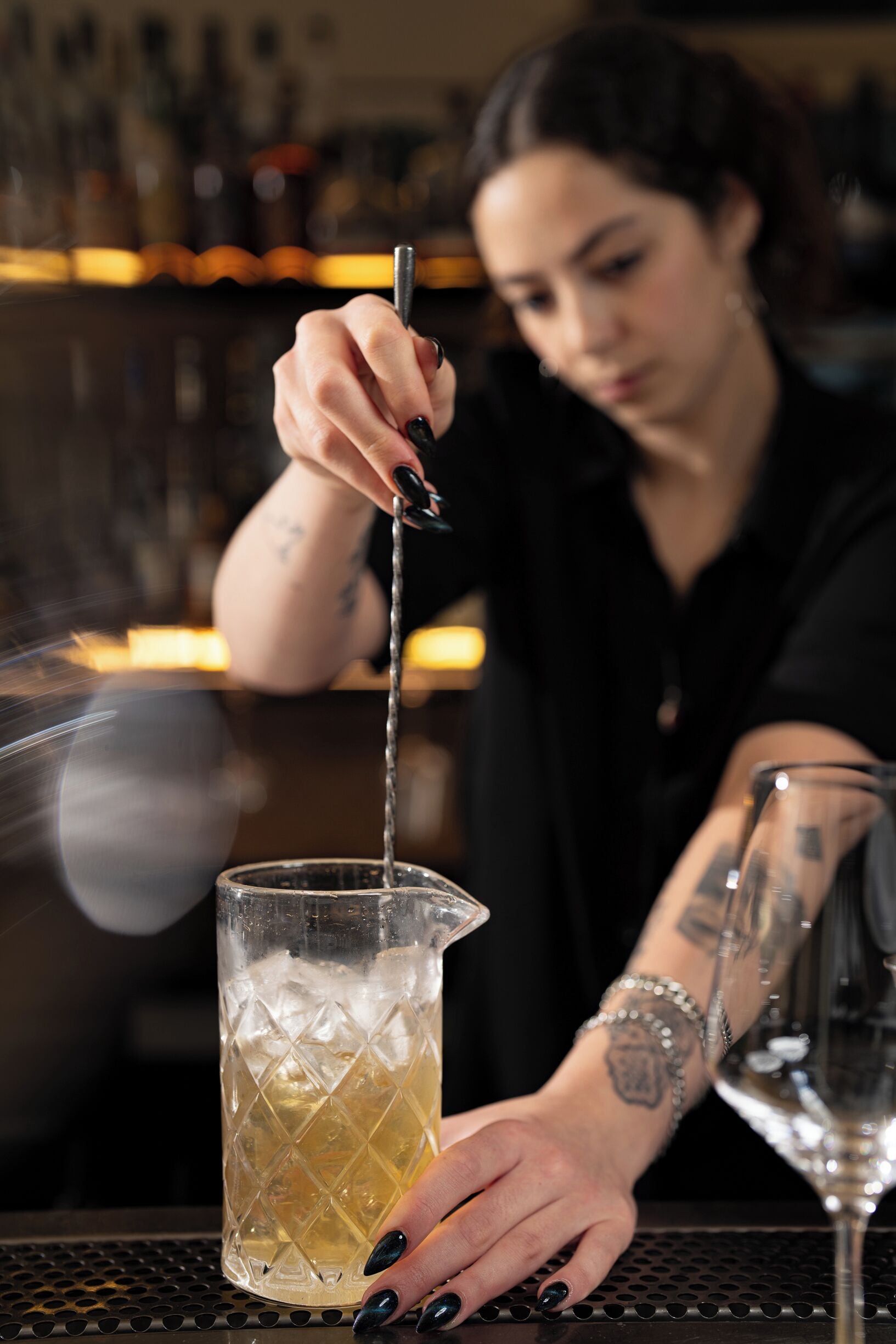 En bartender hælder drik i et glas med lang stilk.