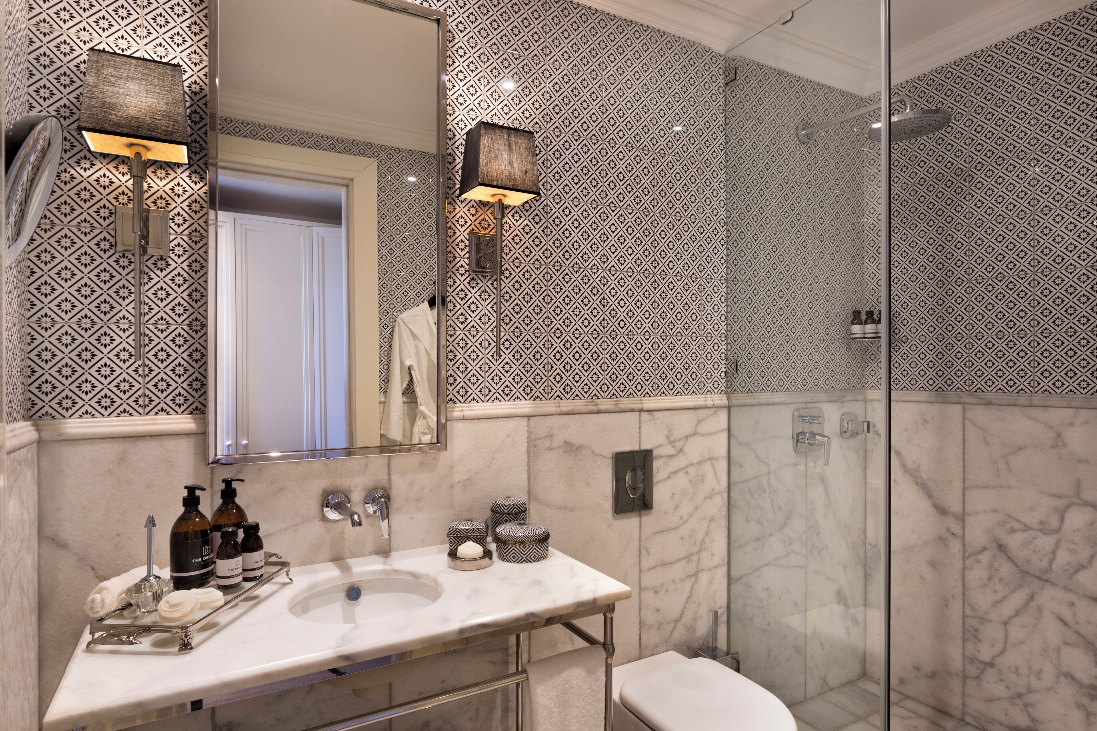 Un baño moderno con un lavabo de mármol, ducha con mampara de vidrio y paredes con diseño.