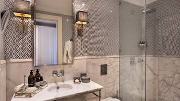 Un baño moderno con un lavabo de mármol, ducha con mampara de vidrio y paredes con diseño.