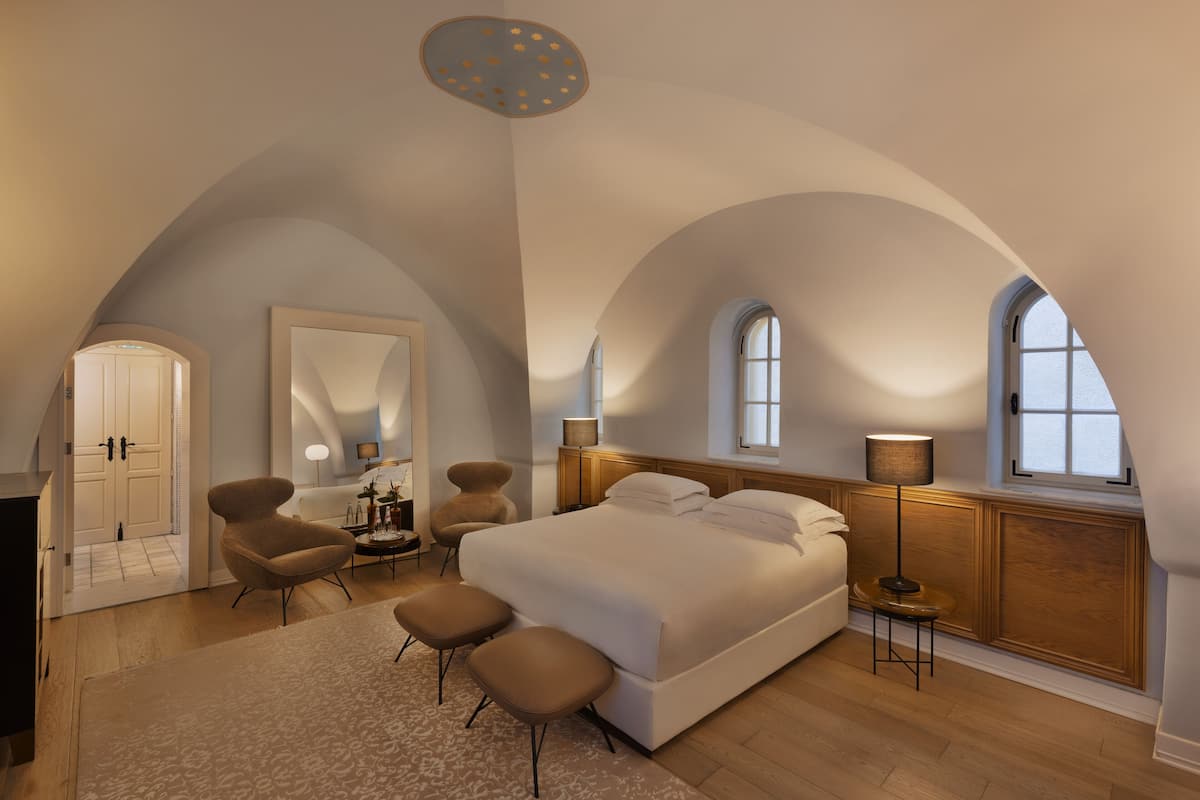 Une chambre spacieuse avec un grand lit, un coin salon avec des fauteuils et une petite table.