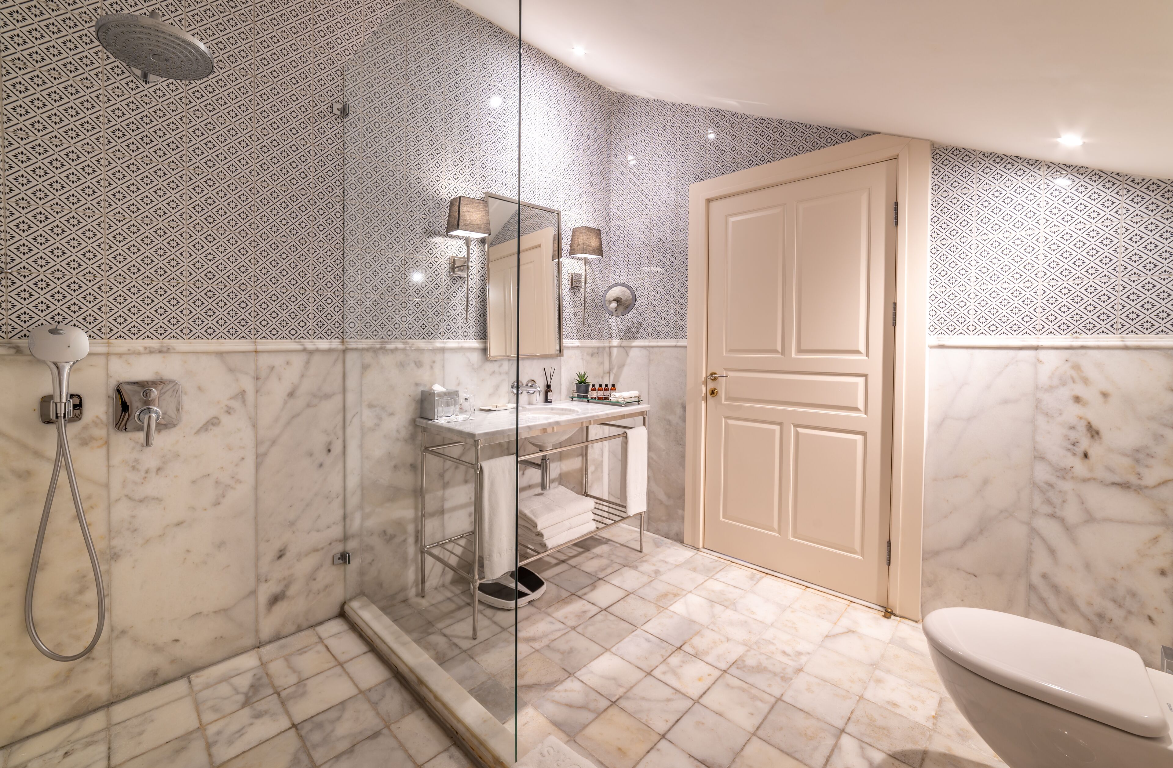 Un baño con ducha envuelta en vidrio, un lavamanos con espejo y un inodoro.