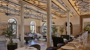 A spacious dining area with high ceilings, marble columns, and a long table set for a meal. - The Drisco Hotel Tel Aviv - Relais & Châteaux (Tel Aviv)