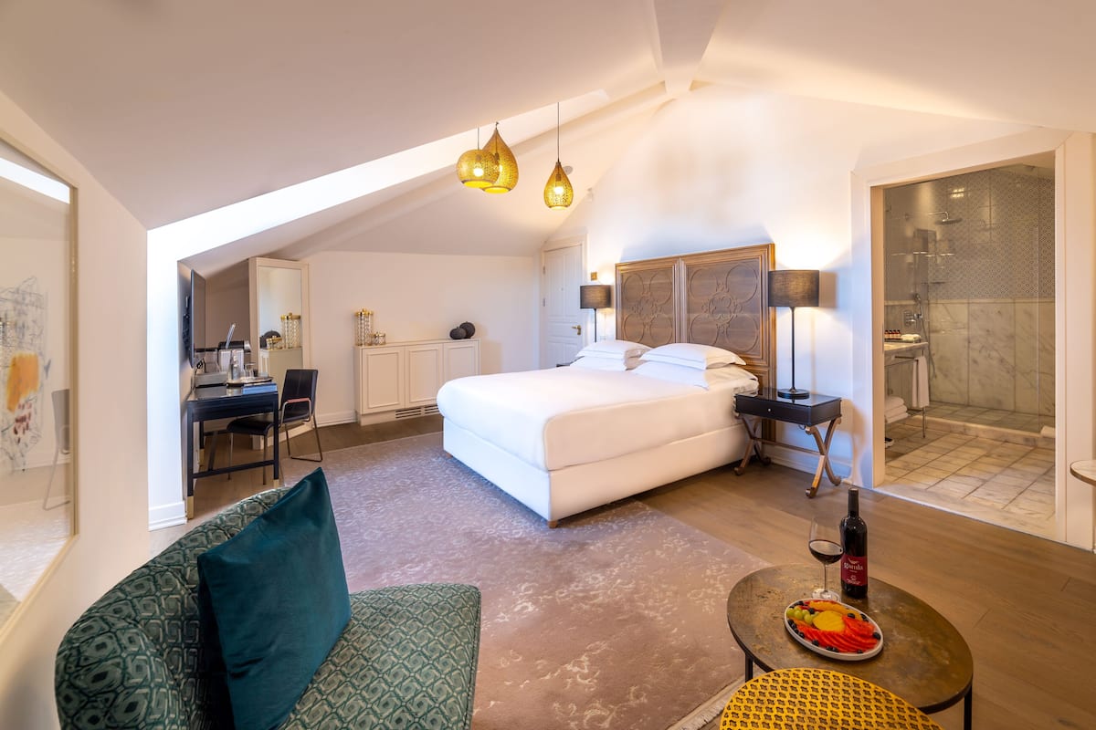 Une chambre d’hôtel moderne dotée d’un grand lit, d’un bureau, d’un coin salon et d’une salle de bain avec douche.