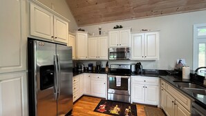 A kitchen with white cabinets, stainless steel appliances, and a wooden ceiling. - Beautiful lake front house, pool table, and fire pit, kayaks,Fall price discount (Hiawassee)