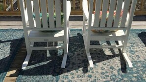 Deux chaises Adirondack blanches, placées face à une plage avec vue sur l’océan.