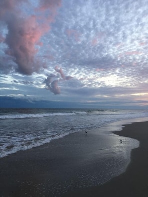 Una playa con olas y cielo nublado.