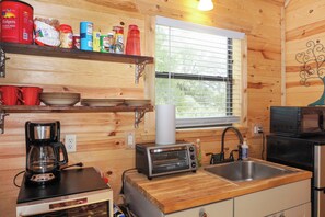 Een compacte keuken met houten wanden, een raam, een broodrooster, een koffiezetapparaat en een magnetron.