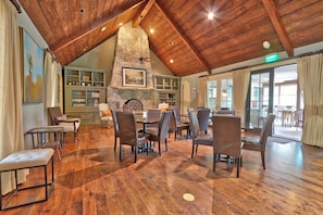 Une salle à manger spacieuse avec un plancher en bois, une cheminée en pierre et un plafond haut avec des poutres apparentes.