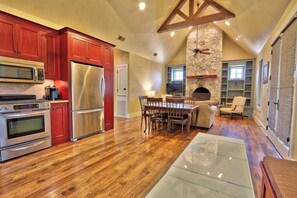 A spacious kitchen with modern appliances, a dining area with a stone fireplace, and a cozy seating area with a view of the outdoors.
