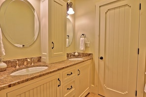 A bathroom with two sinks, a large mirror, a towel rack, and a door. - Fall Creek Vineyards Wine Country Inn | Free Wine Tasting! (Driftwood)