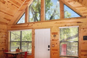 Een houten chalet binnen met een eettafel, stoelen en een witte deur.