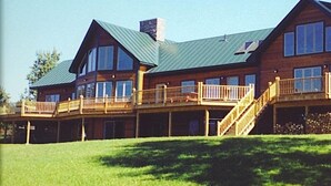 Un'ampia baita di legno con diversi balconi e un portico coperto.