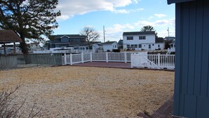 Patio de grava con valla blanca y terraza de madera.