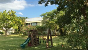 A backyard with a swing set, a slide, and a small palm tree. - Anna's Joye Seawind - Studio Apt, Fully A/C close to beach, 24Hr Security. (Montego Bay)
