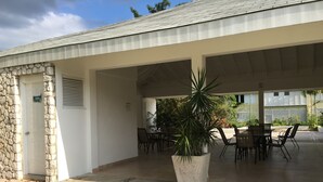 A covered outdoor area with stone walls, a door labeled "Ladies," and a large potted plant. - Anna's Joye Seawind - Studio Apt, Fully A/C close to beach, 24Hr Security. (Montego Bay)