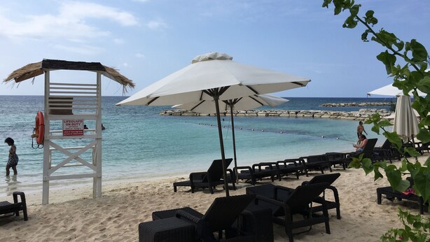 A beach with lounge chairs, umbrellas, and a lifeguard tower. - Anna's Joye Seawind - Studio Apt, Fully A/C close to beach, 24Hr Security. (Montego Bay)