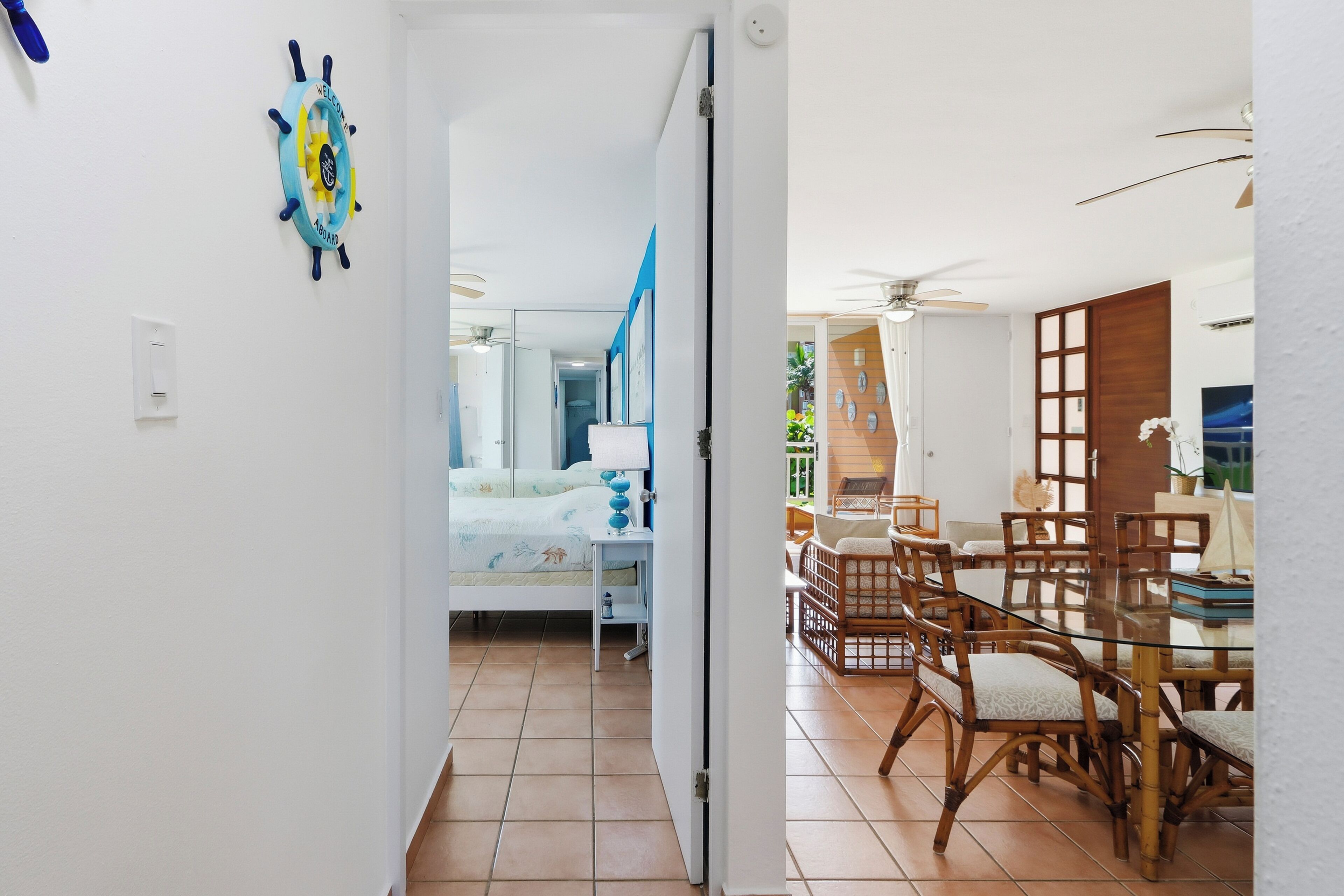 Habitación de hotel con cama, mesita de noche y vista al comedor, que incluye una mesa y sillas.