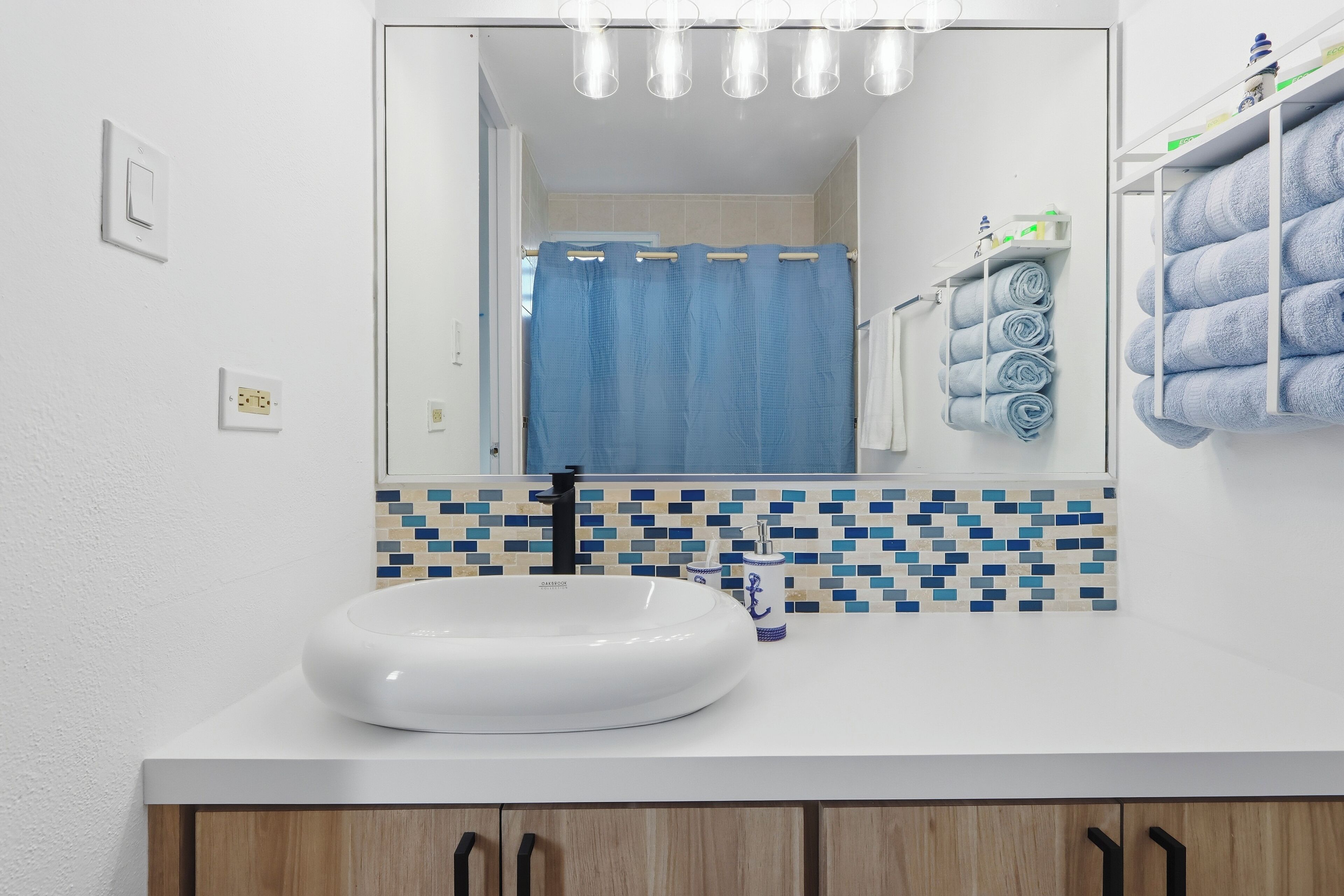 A bathroom with a white sink, a mirror, and a tiled backsplash.