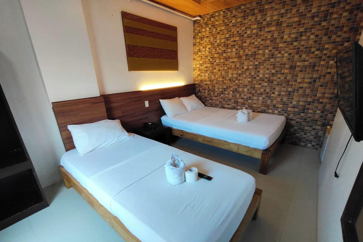 A hotel room with two beds, a wooden headboard, a tiled wall, and a mounted artwork.