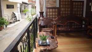 A wooden bench with a potted plant, a rustic wooden table, and a traditional door with a grid pattern. - Taj Guesthouse Boracay (Boracay Island)