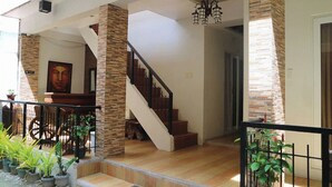 A staircase leading to a second floor, with a chandelier above. There are potted plants and a wooden bench outside. - Taj Guesthouse Boracay (Boracay Island)