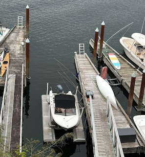 A dock with several boats moored, a ladder, and a kayak.