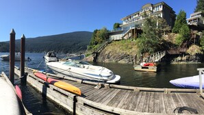 Een jachthaven met aangemeerde boten, een houten pier en een gebouw met balkon dat uitzicht biedt op het water.