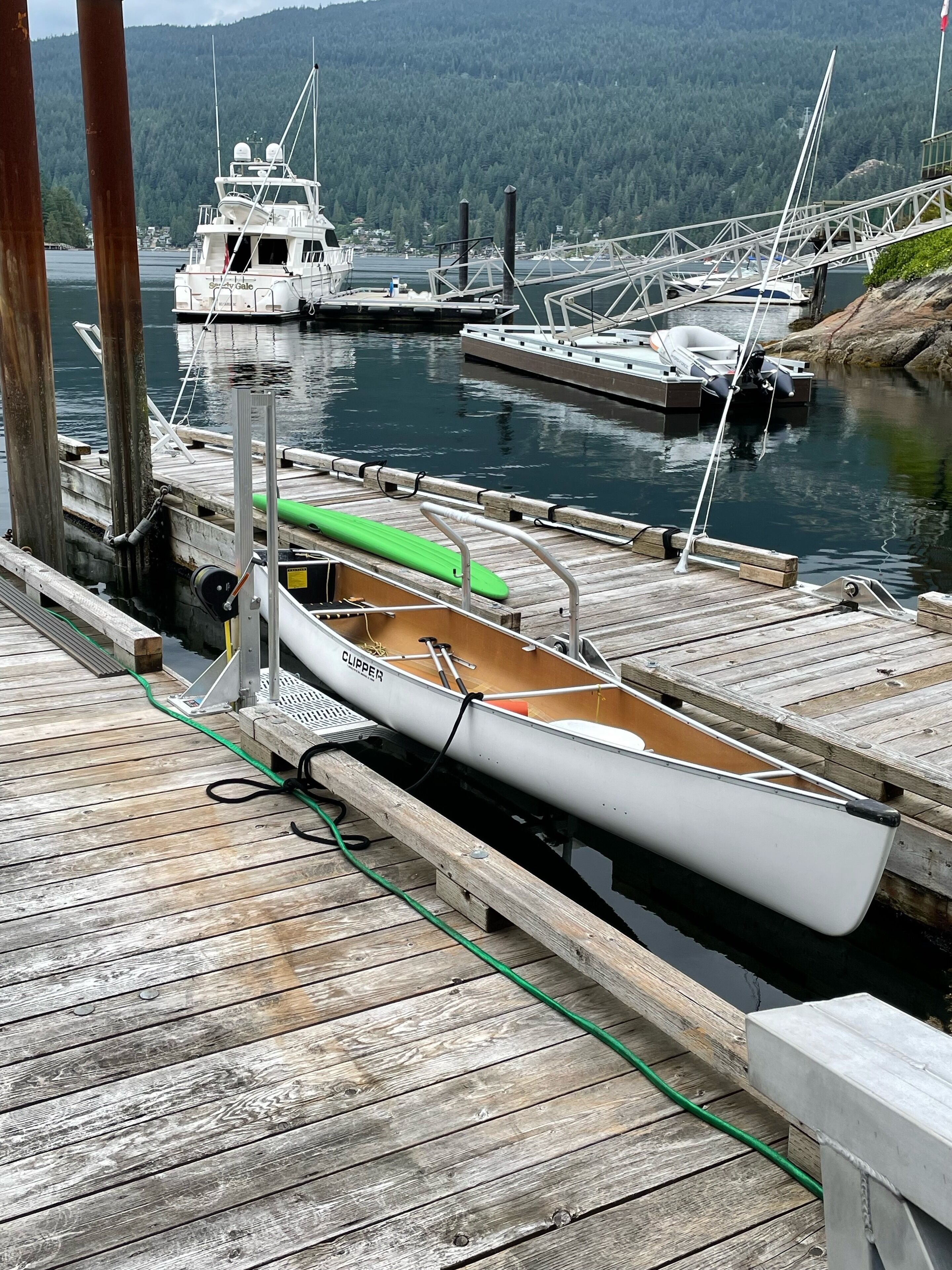 A wooden dock with a rowboat and a green kayak.