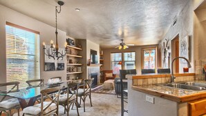 A spacious kitchen with a large island, wooden cabinets, and a dining area with cushioned chairs. - Luxury condo, Walk to Theater & Restaurants, K & Q beds,  private gar. & grill (Park City)