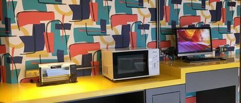 A modern kitchen with a microwave, toaster, and a computer on a yellow countertop.