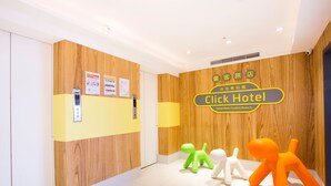 A hotel reception area with a wooden wall, a reception desk, and a sign for the Click Hotel. There are three small, colorful animal-shaped decorations on the floor. - Click Hotel - Taipei Main Station Branch (Taipei)