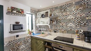 Una cucina con piastrelle decorate, un forno a microonde, un piano cottura e una macchina per il caffè.