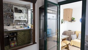 Una cucina compatta con parete di fondo piastrellata, un pensile in legno e un piccolo angolo ristoro con tavolo e sedie.
