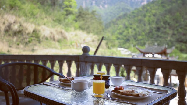 A breakfast table with a view of a mountainous landscape. - National Park MINI Inn - Yangjiajie (Zhangjiajie)