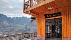 A wooden building with a sign reading "Mini Inn" and a view of a mountainous landscape in the background. - National Park MINI Inn - Yangjiajie (Zhangjiajie)