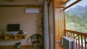 A wooden balcony with a TV, air conditioning unit, and a chair. - National Park MINI Inn - Yangjiajie (Zhangjiajie)