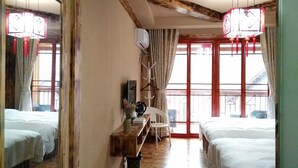 A hotel room with two beds, a wooden nightstand, a chair, and a large window with curtains. - National Park MINI Inn - Yangjiajie (Zhangjiajie)