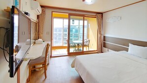 Hotelkamer met een bed, een bureau, een stoel, een televisie en een schuifdeur naar een terras.