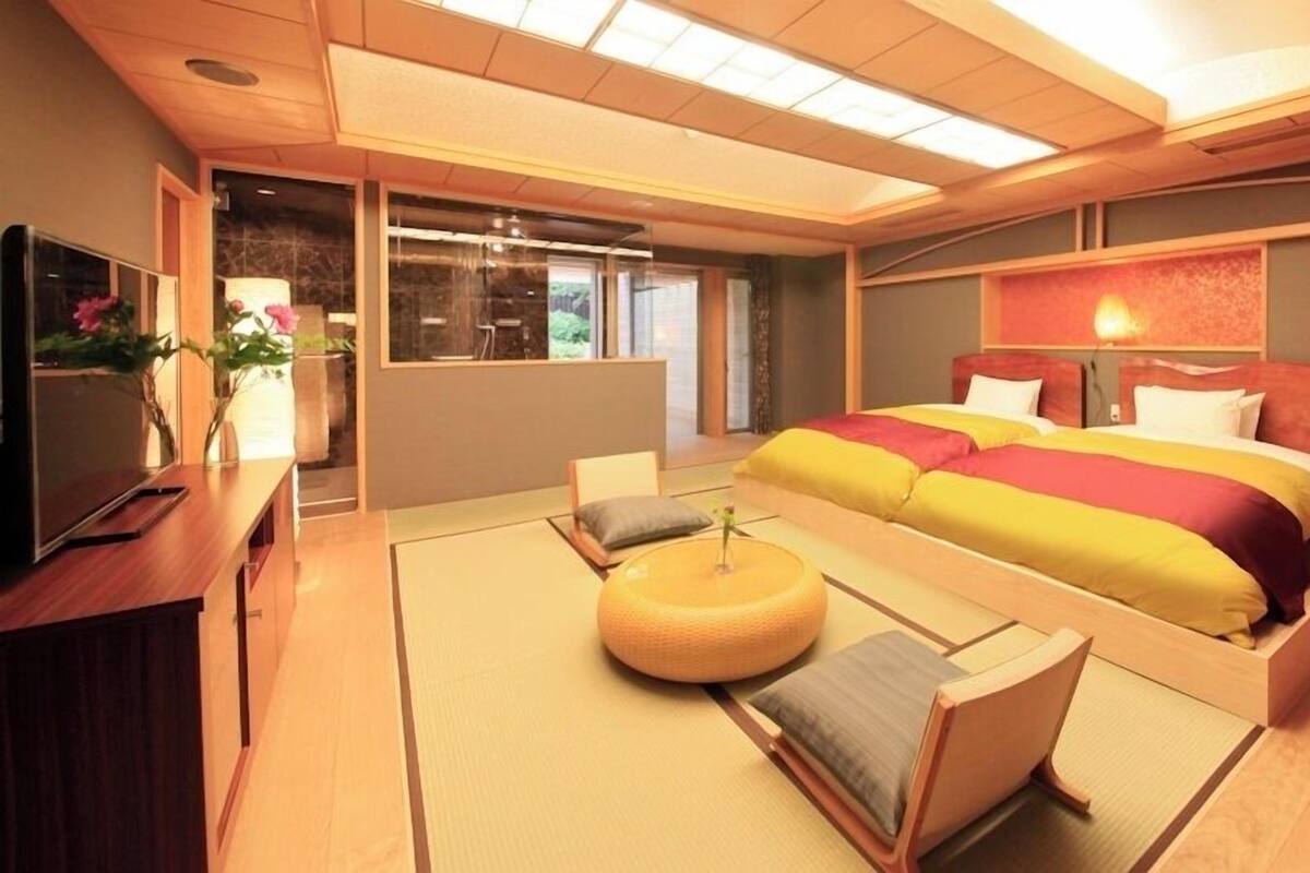 A hotel room with a bed, a TV, a small table, and a window.